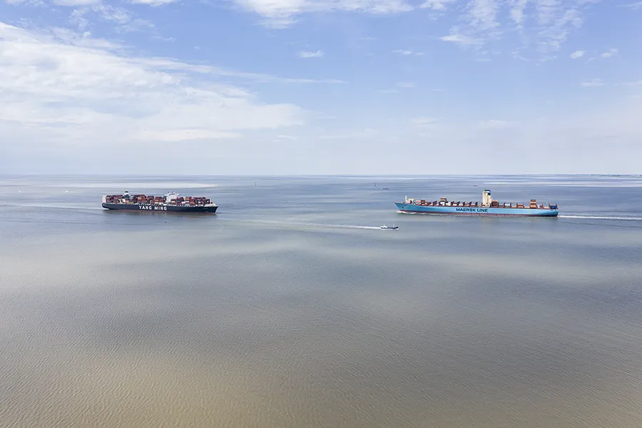Zwei Containerschiffe fahren auf der Elbe in entgegengesetzten Richtungen