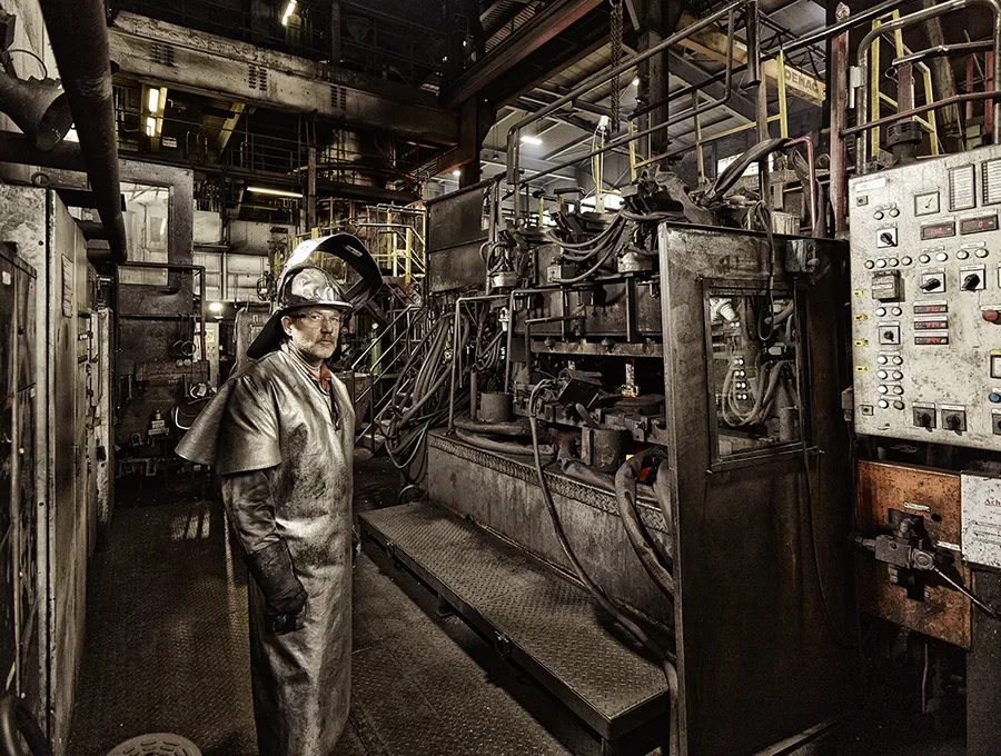 Metallindustrie Fotografie - Arbeiter in Schutzausrüstung vor schwerer Produktionsanlage, authentische Darstellung heißer Prozesse und industrieller Umgebung